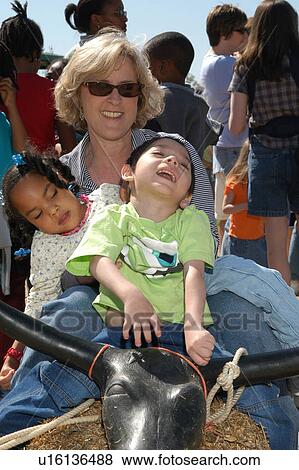 Stock Photo - Two children with disabilities having a blast riding a bull.. Fotosearch