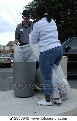 Stock Photography - A man with a disability is emptying the trash with the assistance of a support person.. Fotosearch