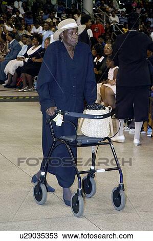 African American woman using her walker for support as she walks into an event with a gathering of other African Americans in an auditorium. View Large Photo Image Stock Image - African American woman using her walker for support as she walks into an event with a gathering of other African Americans in an auditorium.. Fotosearch