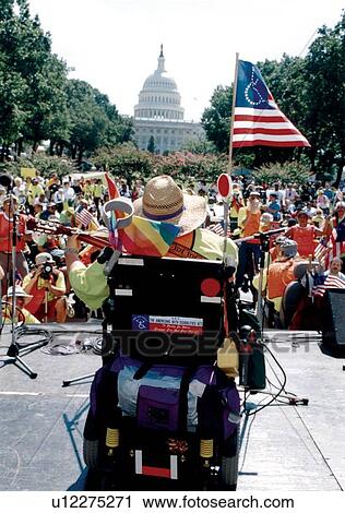 Stock Image - Gay Rights & Disability Rights Activist, utilizing a wheelchair for mobility, performing before a crowd of people in front of the United States Capitol. Event sponsored by ADAPT.. Fotosearch