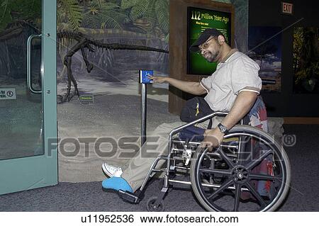 Man with a disability, utilizing a wheelchair for mobility, using an accessible entrance at a museum exhibit. View Large Photo Image Stock Photograph - Man with a disability, utilizing a wheelchair for mobility, using an accessible entrance at a museum exhibit.. Fotosearch