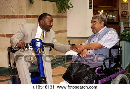 Stock Image - Two men talking during a break at a Disability Activist Conference.. Fotosearch