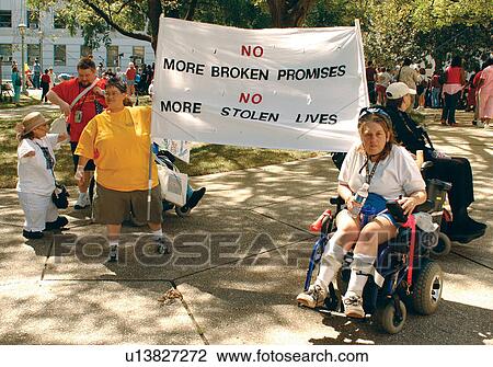 Stock Image - Two women with disabilities (and others) carrying a banner to advocate for people with disabilities to live in the community rather than institutions.. Fotosearch