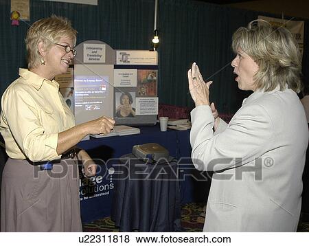 Stock Photo - Two women with hearing impairments/deafness conversing via American Sign Language.. Fotosearch