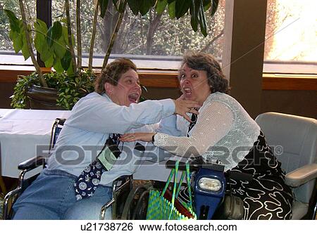 Woman in wheelchair smiling as she hugs and goofs around with woman in scooter. View Large Photo Image Stock Photograph - Woman in wheelchair smiling as she hugs and goofs around with woman in scooter.. Fotosearch