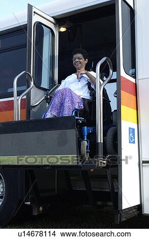 Picture - Woman with a disability (utilizing a wheelchair for mobility) using public transportation to get where she wants to go.. Fotosearch