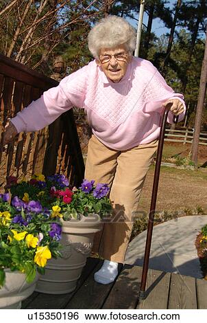 An elderly woman checks on her flowers. View Large Photo Image Stock Photograph - An elderly woman checks on her flowers.. Fotosearch