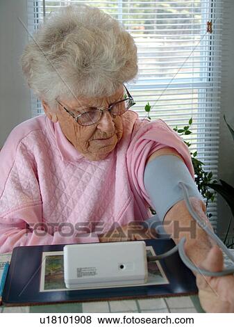 An elderly woman takes her daily blood pressure reading. View Large Photo Image Stock Photo - An elderly woman takes her daily blood pressure reading.. Fotosearch