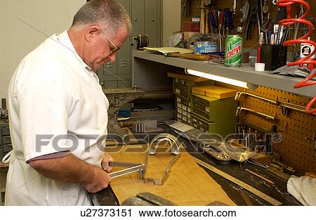 Stock Image - Man repairing a brace used to assist a person with a disability who has mobility impairments.. Fotosearch