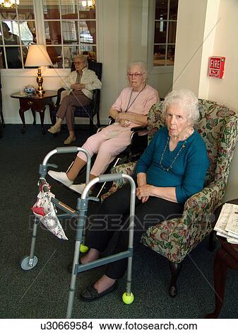 Picture - Two elderly ladies sit together in the lobby of a nursing home.. Fotosearch