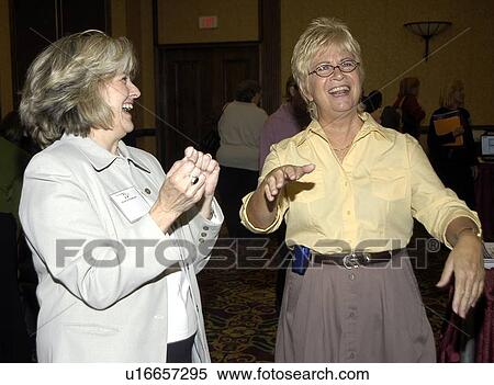 Stock Photography - Two women with hearing impairment laughing and signing to each other.. Fotosearch
