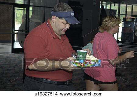 Picture - A man with disabilities getting snacks for a movie.. Fotosearch