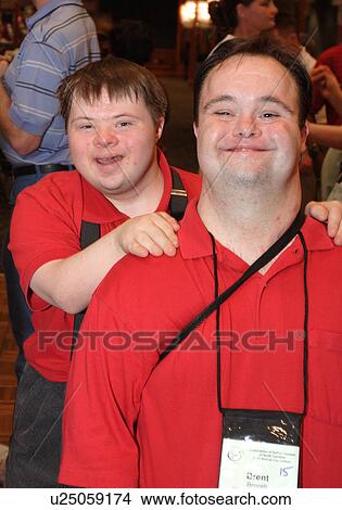 Picture - A man with Down's Syndrome smiling as a male companion puts his arm around his shoulders. . Fotosearch
