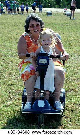 Little girl catching a ride with a friend who utilizes a scooter/cart for mobility. View Large Photo Image Stock Photo - Little girl catching a ride with a friend who utilizes a scooter/cart for mobility.. Fotosearch