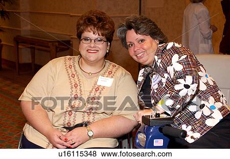 Two friends, both utilizing wheelchairs/scooters for mobility, chatting and laughing after a great day at a disability conference. View Large Photo Image Stock Photo - Two friends, both utilizing wheelchairs/scooters for mobility, chatting and laughing after a great day at a disability conference.. Fotosearch