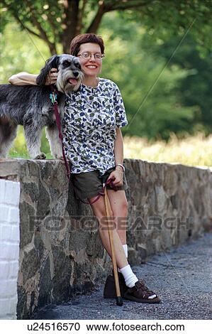 Woman with a physical disability taking a break while walking with her cute, scruffy dog. View Large Photo Image Stock Image - Woman with a physical disability taking a break while walking with her cute, scruffy dog.. Fotosearch