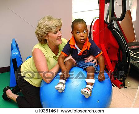 Adorable little boy with multiple disabilities atop a large therapy ball during a session with his physical therapist. View Large Photo Image Stock Image - Adorable little boy with multiple disabilities atop a large therapy ball during a session with his physical therapist.. Fotosearch