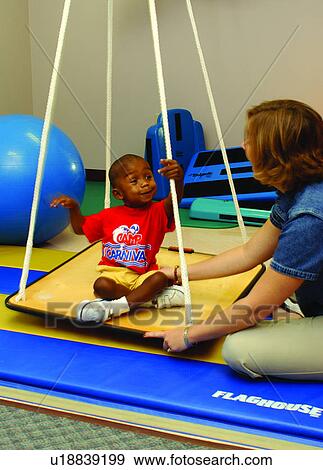 Adorable little boy with multiple disabilities during a therapy session where he is swinging on a modified swing. View Large Photo Image Stock Photo - Adorable little boy with multiple disabilities during a therapy session where he is swinging on a modified swing.. Fotosearch