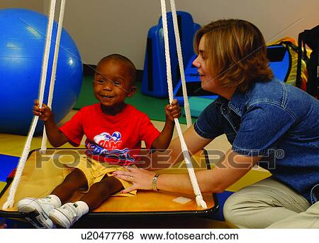 Adorable little boy with multiple disabilities during a therapy session where he is swinging on a modified swing. View Large Photo Image Stock Photo - Adorable little boy with multiple disabilities during a therapy session where he is swinging on a modified swing.. Fotosearch