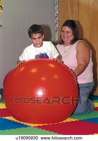Cute little boy who is blind and has other disabilities attempting to roll on the large therapy ball during a session with his physical therapist. View Large Photo Image Stock Image - Cute little boy who is blind and has other disabilities attempting to roll on the large therapy ball during a session with his physical therapist.. Fotosearch