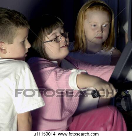 Picture - Girl with Down Syndrome riding an exercise bike while her friends watch how fast she is going.. Fotosearch