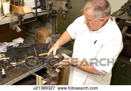 Stock Photo - Man repairing a shoe/brace combination used to assist a person with a disability who has mobility impairments.. Fotosearch