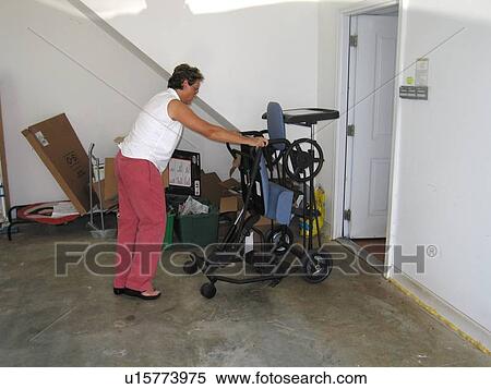 Stock Photography - Mother puts daughterÆs ôstanderö (assistive device) in storage after a therapy session.. Fotosearch