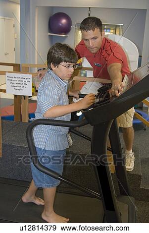 Side view of therapist helping boy with muscular dystrophy push buttons on the treadmill. View Large Photo Image Stock Photo - Side view of therapist helping boy with muscular dystrophy push buttons on the treadmill.. Fotosearch