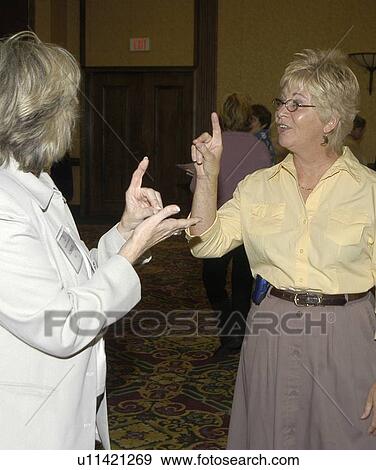 Stock Photo - Two women with hearing impairments/deafness conversing via American Sign Language.. Fotosearch