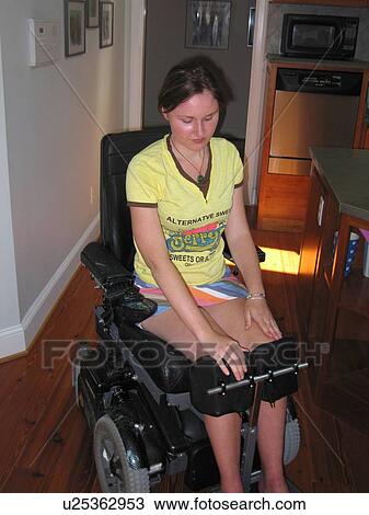 Stock Image - Young woman does physical therapy in her electric wheelchair.. Fotosearch