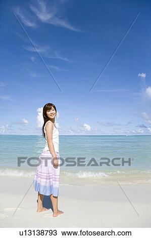 Portrait of a young woman standing on beach, smiling and looking back, Saipan, USA View Large Photo Image Stock Image - Portrait of a young woman standing on beach, smiling and looking back, Saipan, USA . Fotosearch