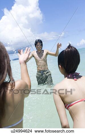 Three young people playing in the sea, smiling, Saipan, USA View Large Photo Image Picture - Three young people playing in the sea, smiling, Saipan, USA . Fotosearch