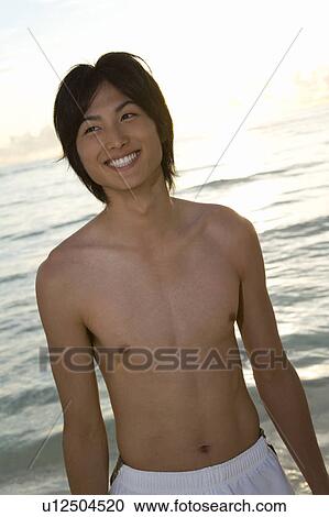 Young man standing on beach, smiling, Saipan, USA View Large Photo Image Stock Image - Young man standing on beach, smiling, Saipan, USA . Fotosearch