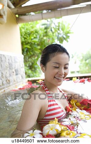 Stock Image - Young woman in a bath full of flowers, Saipan. Fotosearch