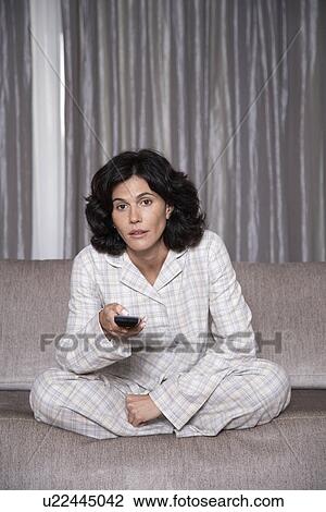 Mid adult woman watching TV on sofa View Large Photo Image Stock Image - Mid adult woman watching TV on sofa. Fotosearch
