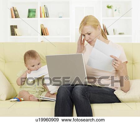 Stock Photo - Mother Doing Paperwork Beside Baby Boy. Fotosearch