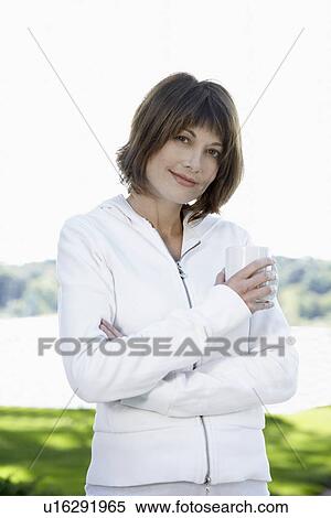 Stock Photography - Woman in hooded sweatshirt holding mug (portrait). Fotosearch