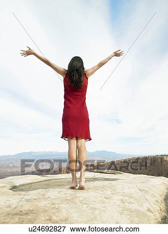 Mid adult woman in red dress raising arms, rear view, rock strata in background View Large Photo Image Stock Photo - Mid adult woman in red dress raising arms, rear view, rock strata in background. Fotosearch