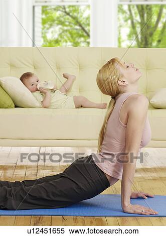 Stock Photography - Mother Doing Yoga, Baby Boy in Background. Fotosearch