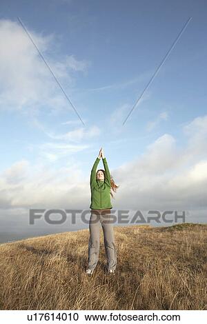 Stock Image - Young woman meditating on cliff. Fotosearch