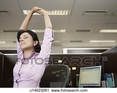 Young woman stretching at office desk View Large Photo Image Stock Image - Young woman stretching at office desk. Fotosearch