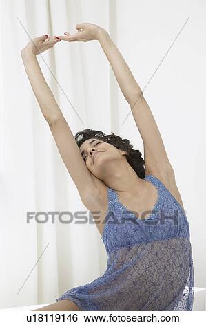 Stock Photograph - Young woman stretching in nightdress. Fotosearch
