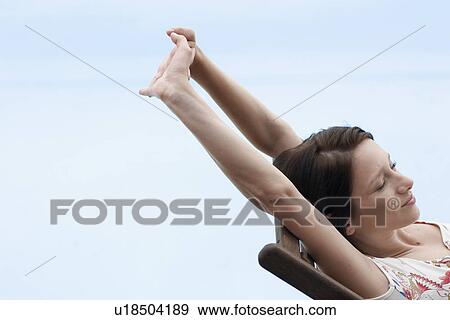 Stock Photo - Young woman stretching on lounge chair. Fotosearch