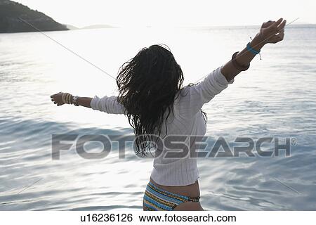 Young woman with arms stretched by ocean View Large Photo Image Stock Photograph - Young woman with arms stretched by ocean. Fotosearch