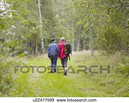 Two women walking through a forest with a backpack smiling. View Large Photo Image Stock Photo - Two women walking through a forest with a backpack smiling.. Fotosearch