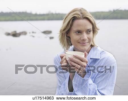 Woman by the water holding a mug. View Large Photo Image Stock Image - Woman by the water holding a mug.. Fotosearch