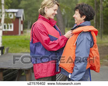 Woman helping another woman with her life jacket smiling. View Large Photo Image Stock Image - Woman helping another woman with her life jacket smiling.. Fotosearch