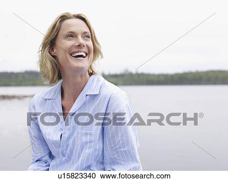 Woman laughing outdoors by the water. View Large Photo Image Stock Image - Woman laughing outdoors by the water.. Fotosearch