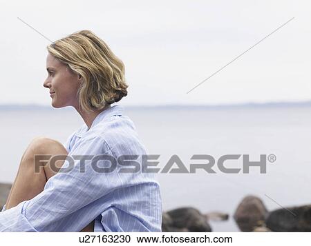 Woman sitting by the water relaxing. View Large Photo Image Stock Image - Woman sitting by the water relaxing.. Fotosearch