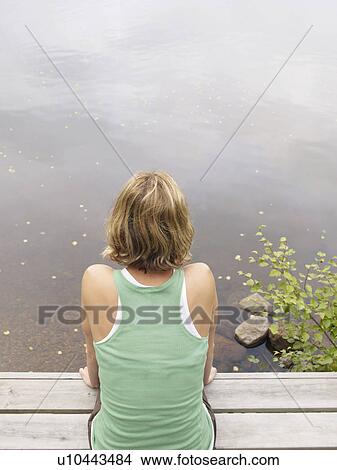 Picture - Woman sitting on dock.. Fotosearch